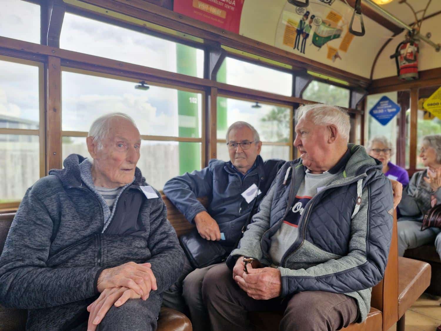 Three gentlemen sharing a laugh on a heritage tram
